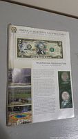Laminated display showing $2 bill, two Yellowstone National Park quarters, and park information.