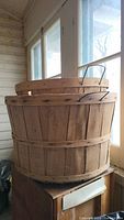 Side view of the stack of three wooden bushel baskets showing natural wood slats and metal handles.