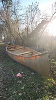 Side profile of tan canoe on ground