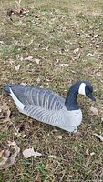 Side view of Canada goose decoy showing detailed feather painting, white cheek patch, and black head and neck on natural grass background.
