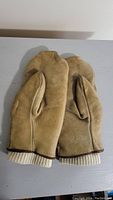 Front view of vintage brown leather gloves showing textured leather and wool cuffs