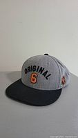 Front view of grey and black snapback hat with 'Original 6' text and black bill