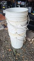 Side view of stack of six white plastic buckets showing dirt marks and usage.
