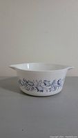 Side view of the white glass casserole dish with blue floral pattern and pouring spout.