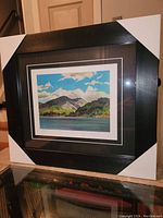 Photo of the framed fine art print wrapped with corner protectors showing the full piece, frame, and matting.