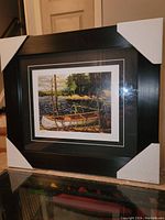 Framed Tom Thomson fine art print showing the overall presentation with black frame and protective corner covers.