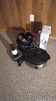 Five kitchen appliances placed on carpet: Instant Pot, SodaStream, Crockpot slow cooker, Slap Chop hand chopper, Black & Decker waffle maker visible