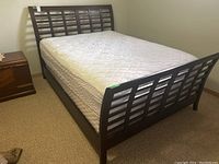 Full view of bed showing headboard and footboard structure, mattress and box spring, wood veneer frame