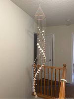 Front view of the ceramic hanging ceiling decor showing spiral arrangement of ceramic bells on metal ring frame.