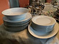 Stack of dinner plates and side plates showing delicate floral pattern and silver rim
