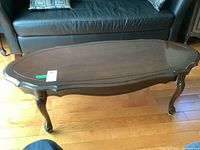 Photo of Deilcraft wooden coffee table with curved cabriole legs and hewn scalloped edges on the top, showing full tabletop and legs against a wood floor.