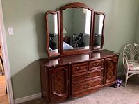 Front view showing dresser with four drawers, two side cupboards, and three-panel mirror attached.