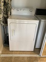 Front view of white GE dryer in place showing door and controls