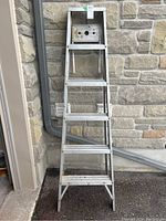 Front view of aluminum stepladder showing five steps and top platform with holes.