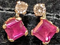 Close-up photo of pair of ruby and diamond stud earrings, showing square ruby stones and round diamonds on 10K gold setting.