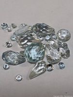 Multiple faceted aquamarine gemstones arranged on a white surface showing various cuts and sizes.