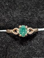 Front-facing view of sterling silver ring featuring oval emerald cabochon and heart-shaped designs