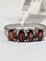 Front view of sterling silver garnet ring showing four oval garnet stones set in pronged settings.