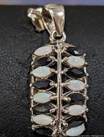 Front view of the sterling silver pendant showing alternating marquise cabochon opal and faceted onyx stones mounted in prong settings.