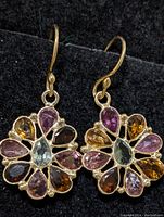 Pair of gold-tone sterling silver drop earrings with multi-color tourmaline arranged in a flower pattern on black background.
