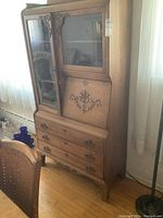 Front right view of oak side-by-side secretary cabinet showing upper glass doors, carved motifs and lower drawers.