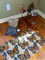 Photo of entire lot showing three bird sculptures on stands, two concrete turtles, and butterfly mat on wooden floor