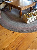 Oval braided area rug under a wooden table showing overall condition and size relative to furniture.