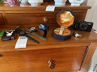 Overview of all items on wooden dresser including camera, watches, playing cards, and watch case