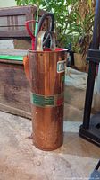 Copper-colored fire extinguisher showing entire body and hose.