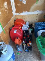 Overview photo of all items in corner showing accurate count and condition of gas cans and fluid bottles.