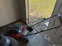 Photo showing full side view of Craftsman push mower in shed, visible red and black body with four wheels and handle.