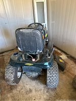 Rear view of mower showing detached seat base, turf tires, deck underside