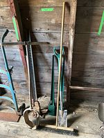 Front view of full lot showing post hole digger, post spikes, jack, push broom, and shovel leaning against wooden wall