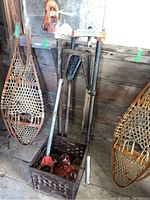 Overall view of TriStand folded with crate of attachments and snowshoes on wall