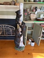 Full view of tall birch tree sculpture with three bears climbing, showing size and setting near fireplace and shelves.