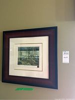 Framed signed Tom Thomson print hanging on wall, visible label with dimensions 7.5x9
