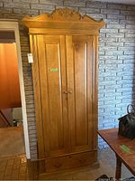 Front view of full wardrobe showing carved top pediment, paneled double doors and base drawer