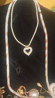Necklaces displayed on black velvet with pearled beads and heart-shaped pendant visible
