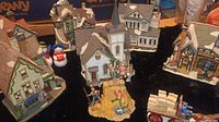 Overview showing multiple ceramic houses and figurines including snow people and hay jumping figures.