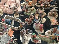 Wide view showing many small figurines representing town people, animals, and a nativity scene with snow and fence pieces