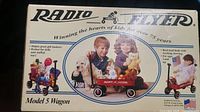 Boxed Radio Flyer Model 5 Wagon showing front panel with photo of children and pets in the wagon, brand logo, and product details.