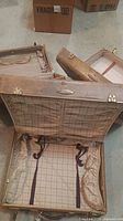 Three vintage Samsonite suitcases in open view showing plaid interiors and securing straps, tan exterior with gold clasps and leather handles