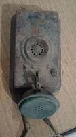 Rusty vintage phone base showing front with rotary contact area and worn exterior