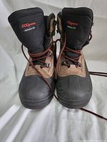 Front view of the Columbia men's boots showing black and brown color design, red/brown laces, and 200 grams Thermarator insulation label on tongue.