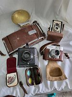 All vintage cameras and camera accessories arranged for viewing on white backdrop