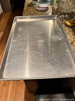 Top view of large aluminum baking sheet showing surface wear and dimensions.
