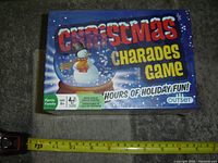 Photo of the sealed Christmas Charades game box with holiday graphic, snowman inside a snow globe, and brand Outset Games.