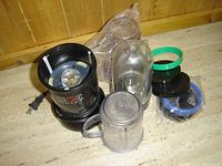 Full view of Magic Bullet Model MBI001B blender base with containers and accessories arranged around it on a countertop or table.