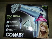 Photo of Conair 1875W electric hair dryer in box with multi-setting styler and included attachments such as diffuser, concentrator, and cushion brush.