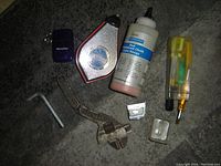 Photo of various hand tools including wrench, hex key, chalk line reel, oil bottle, screwdriver with bit, blue Starkley case, and metal blade accessories.